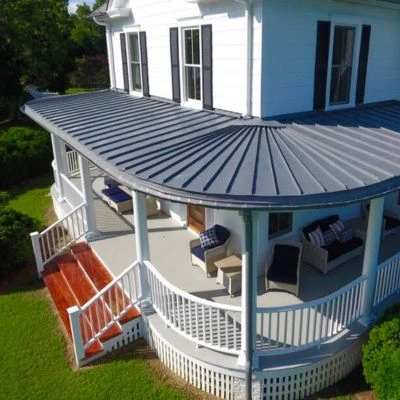A white house with a wraparound porch and a new roof installed by Stevens Roofing