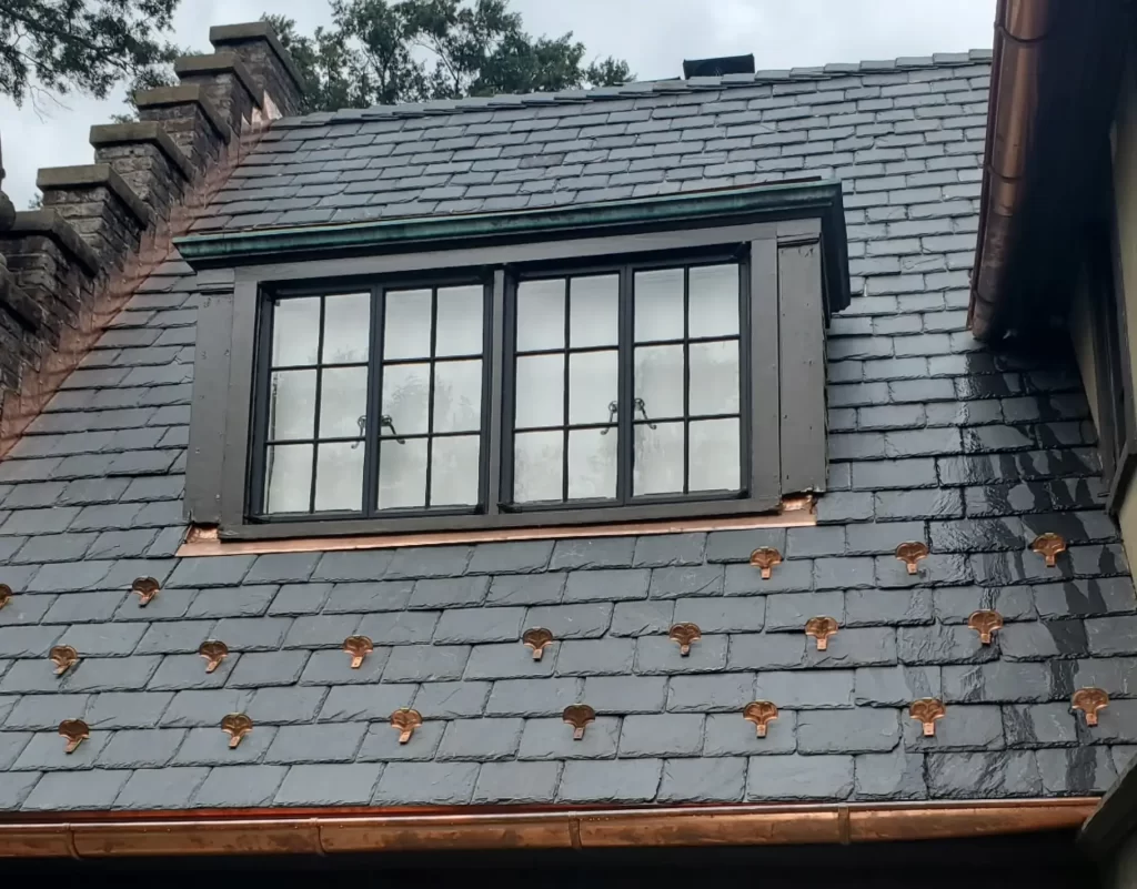 Slate roof repair around a dormer window with copper flashing and slate shingles by a professional roofing contractor, Stevens Roofing.