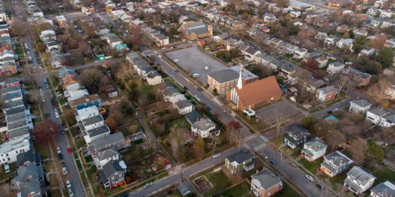 Aerial drone view of a densely packed residential suburban neighborhood with various types of roofing.