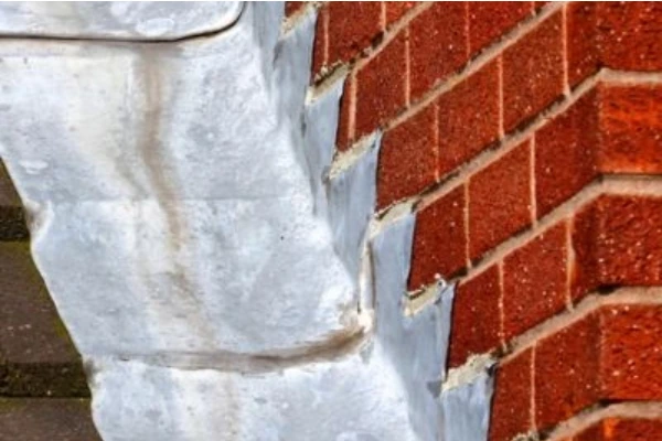 Deteriorating chimney flashing on a brick chimney showing separation and wear that can lead to roof leaks