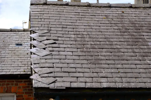 Slate roof tiles slipping out of place along the roof edge due to nail fatigue or fastener failure
