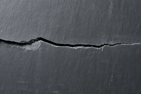 Close-up of a cracked slate tile identified during roof maintenance